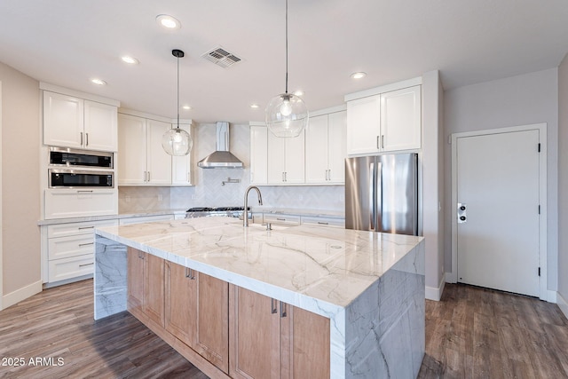 kitchen featuring a large island with sink, appliances with stainless steel finishes, and white cabinets