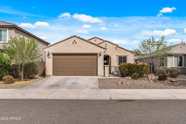 mediterranean / spanish-style home with an attached garage, fence, concrete driveway, a gate, and stucco siding