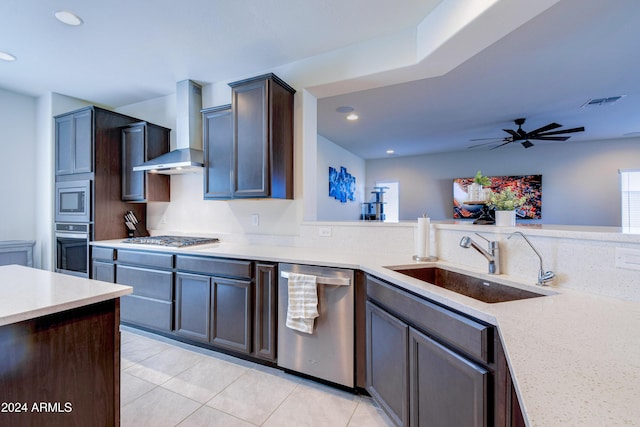 kitchen featuring wall chimney exhaust hood, dark brown cabinetry, stainless steel appliances, sink, and light tile patterned floors