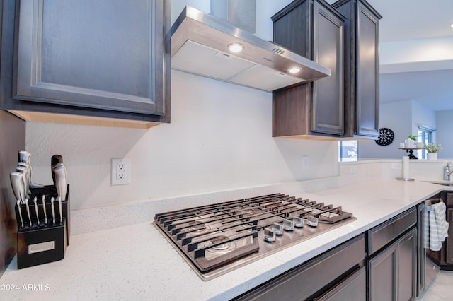 kitchen featuring light stone counters, wall chimney exhaust hood, and stainless steel gas cooktop