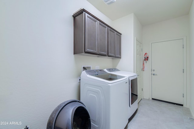 clothes washing area with cabinets and separate washer and dryer