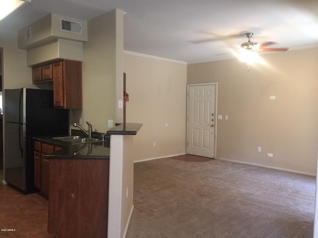 kitchen with visible vents, brown cabinetry, a peninsula, crown molding, and a sink