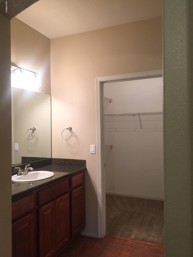 bathroom featuring tile patterned flooring, a walk in closet, and vanity