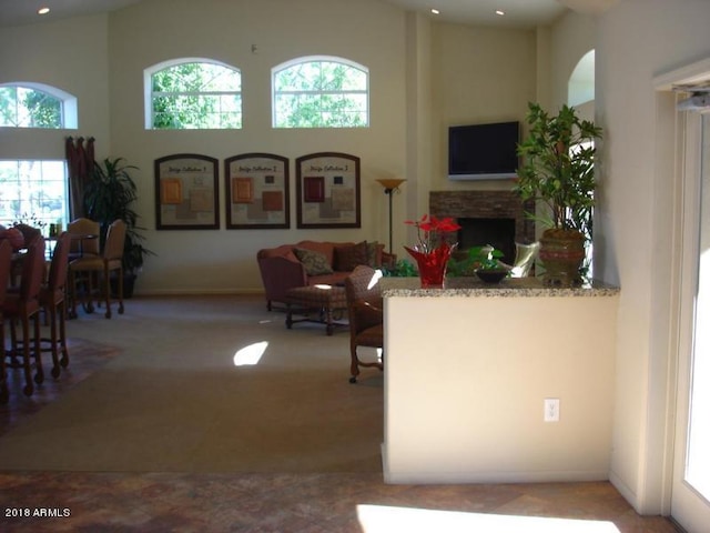 living area featuring a fireplace, a high ceiling, and light colored carpet