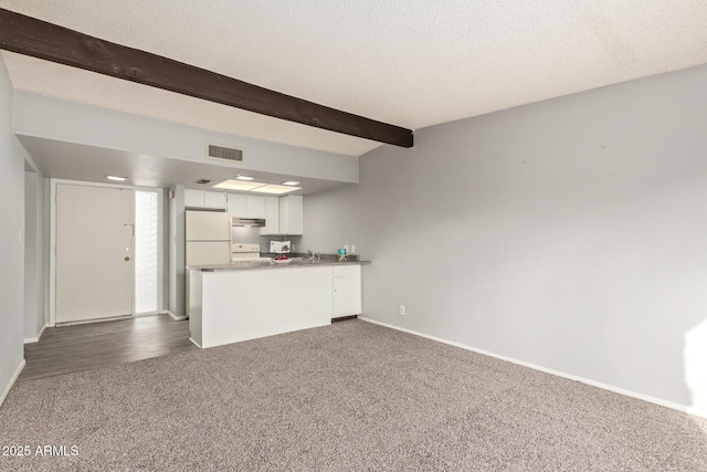 unfurnished living room featuring sink, a textured ceiling, beam ceiling, and dark colored carpet