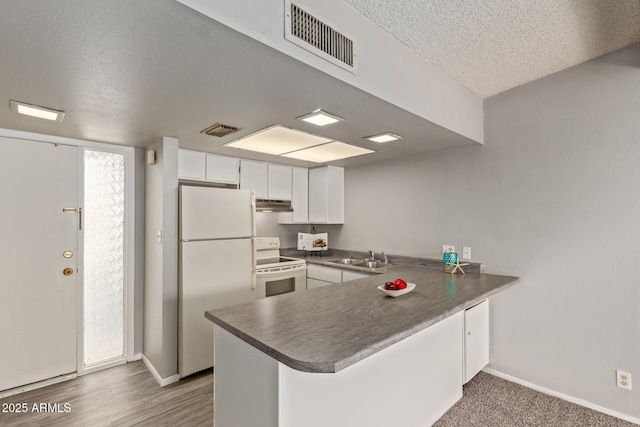 kitchen with white appliances, kitchen peninsula, a textured ceiling, white cabinets, and sink