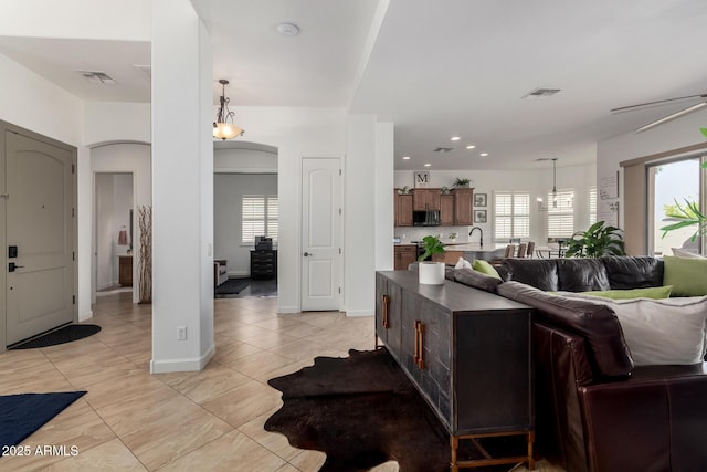 1804 W Magdalena Ln, Phoenix, AZ 85041 - living area featuring light tile patterned floors, healthy amount of natural light, arched walkways, baseboards, and recessed lighting