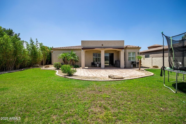 1804 W Magdalena Ln, Phoenix, AZ 85041 - back of house with a trampoline, a patio, and stucco siding
