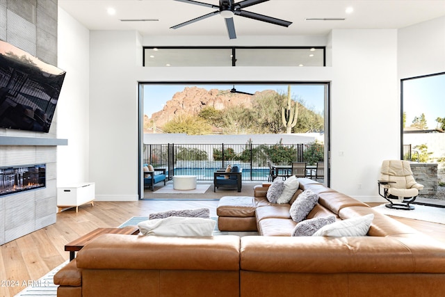 living room featuring hardwood / wood-style flooring, ceiling fan, and a fireplace