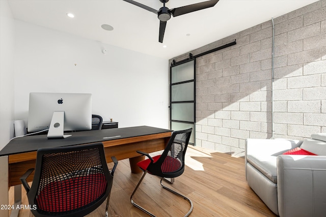 office featuring ceiling fan, a barn door, and light hardwood / wood-style floors