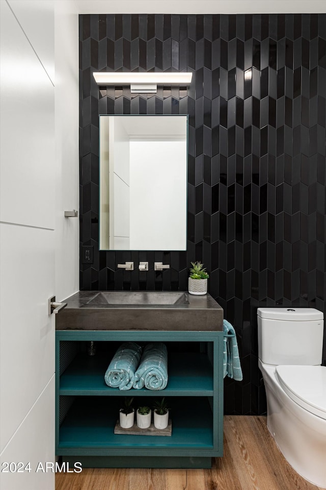 bathroom with wood-type flooring, toilet, tile walls, and vanity