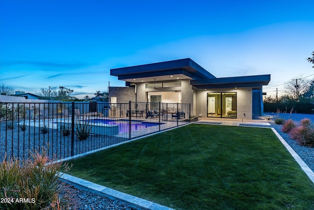 back house at dusk featuring a fenced in pool, a yard, and a patio area