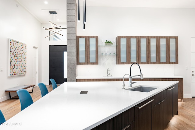 kitchen featuring pendant lighting, sink, light hardwood / wood-style flooring, and dark brown cabinetry