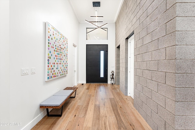 doorway to outside with brick wall, ornamental molding, and light hardwood / wood-style flooring