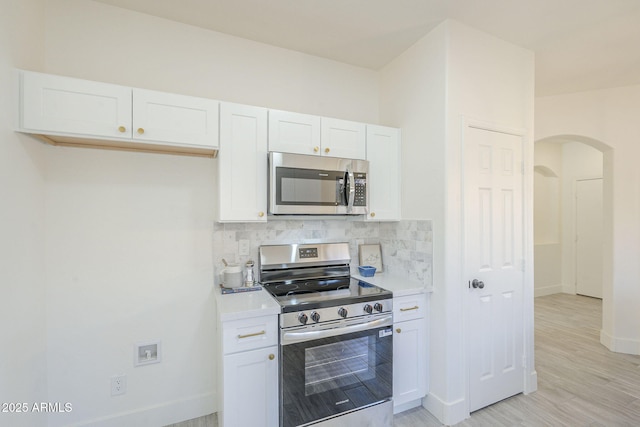 6731 W Northview Ave, Glendale, AZ 85303 - kitchen with stainless steel appliances, arched walkways, baseboards, tasteful backsplash, and white cabinetry