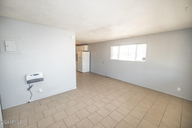 tiled spare room featuring a textured ceiling