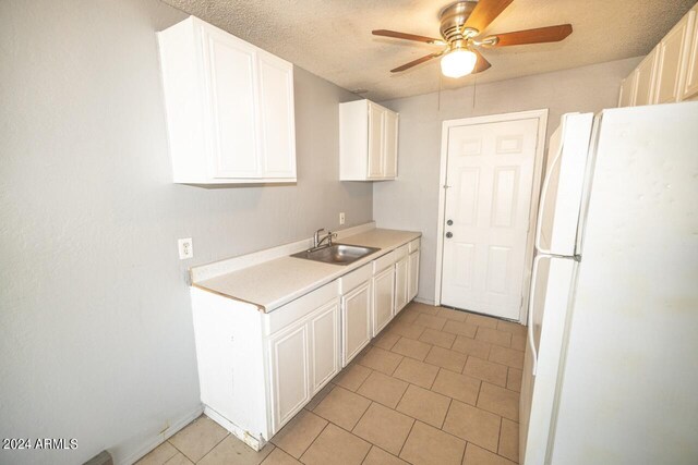 kitchen featuring a textured ceiling, white fridge, sink, ceiling fan, and white cabinets