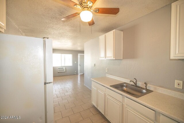 kitchen featuring a wall mounted AC, sink, white fridge, ceiling fan, and a textured ceiling