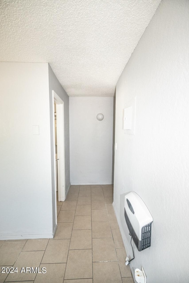 corridor with a textured ceiling and light tile patterned floors