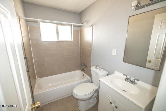 full bathroom with toilet, tile patterned floors, vanity, a textured ceiling, and tiled shower / bath combo