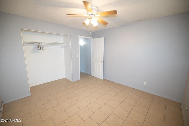 unfurnished bedroom with a textured ceiling, ceiling fan, a closet, and light tile patterned flooring