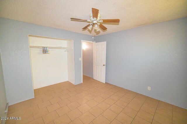 unfurnished bedroom with a textured ceiling, ceiling fan, and a closet