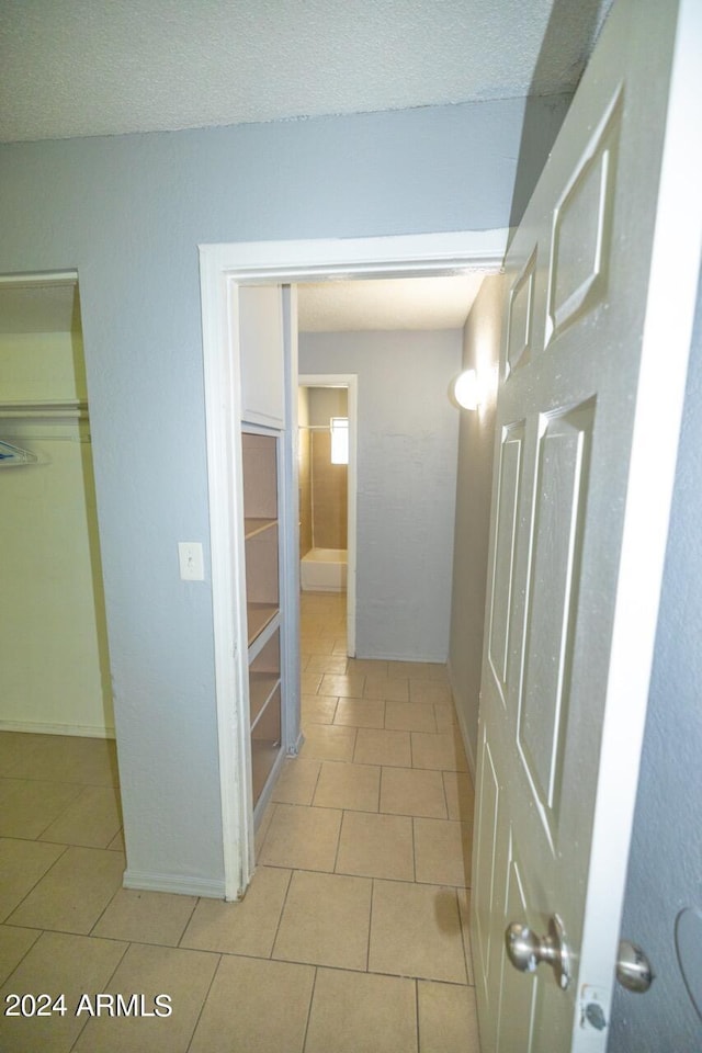 hallway featuring a textured ceiling and light tile patterned floors