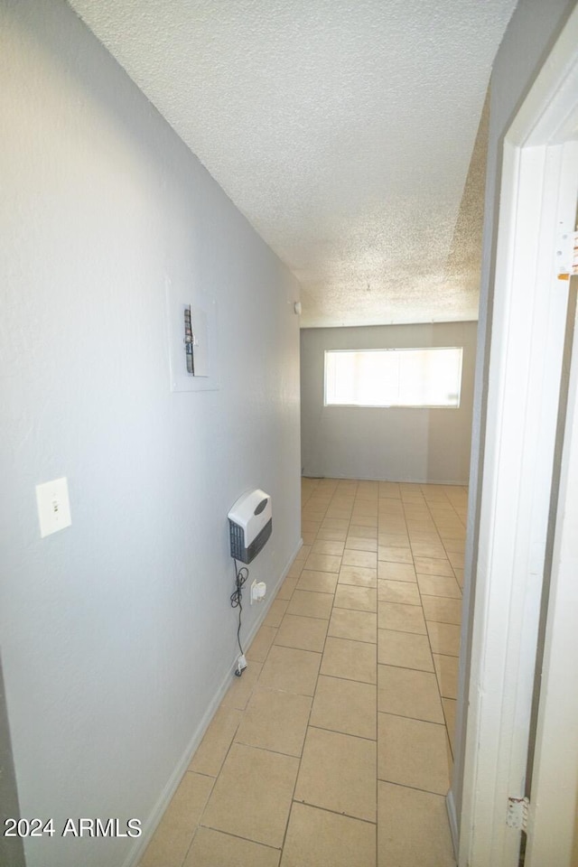 hall featuring light tile patterned flooring and a textured ceiling