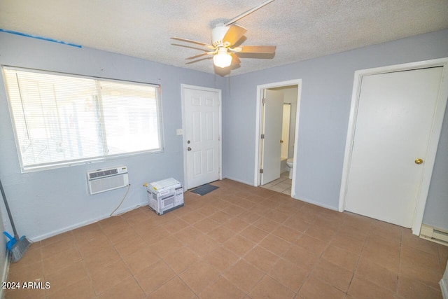 unfurnished bedroom featuring ceiling fan, a wall unit AC, a textured ceiling, and ensuite bath