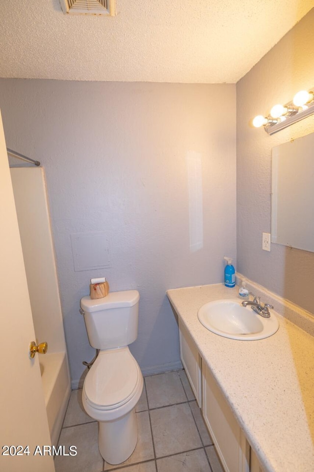 full bathroom with vanity, toilet, tile patterned floors, and a textured ceiling