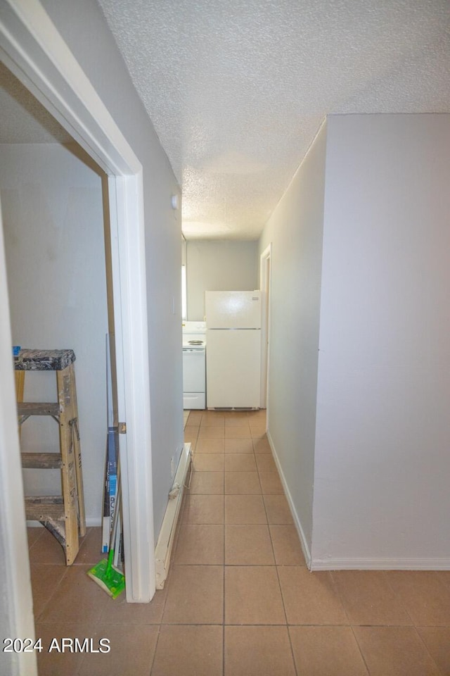 hallway with a textured ceiling and light tile patterned floors