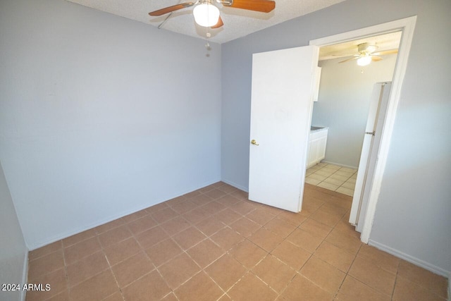 tiled empty room with a textured ceiling and ceiling fan