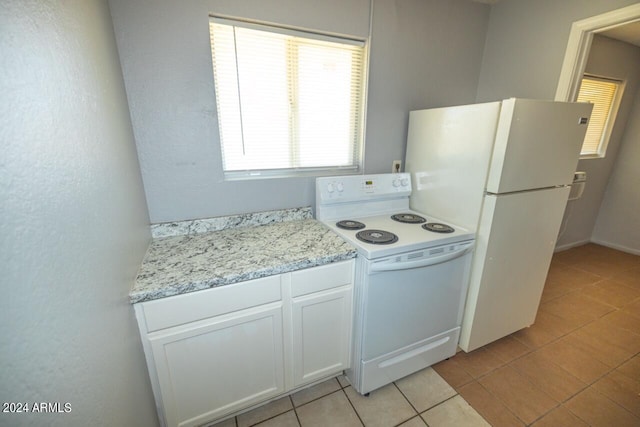 kitchen with plenty of natural light, light stone countertops, white appliances, and white cabinets