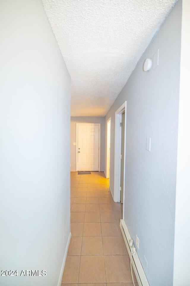 hallway featuring light tile patterned floors and a textured ceiling