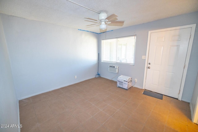 empty room with a textured ceiling, ceiling fan, and a wall unit AC