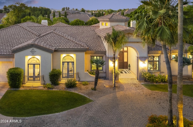 mediterranean / spanish-style house with a lawn and french doors