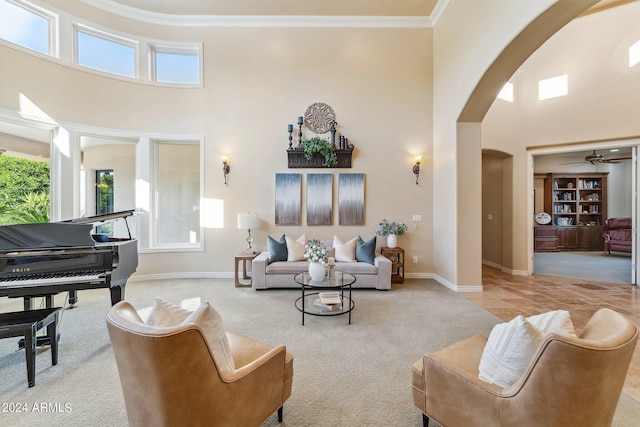 carpeted living room featuring ceiling fan, ornamental molding, and a high ceiling