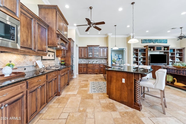 kitchen with a kitchen island, a breakfast bar area, appliances with stainless steel finishes, and dark stone counters