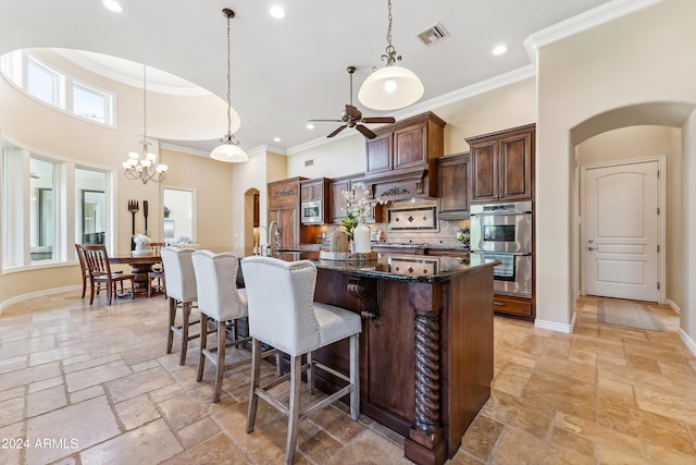 kitchen with ceiling fan with notable chandelier, stainless steel appliances, a spacious island, a high ceiling, and hanging light fixtures