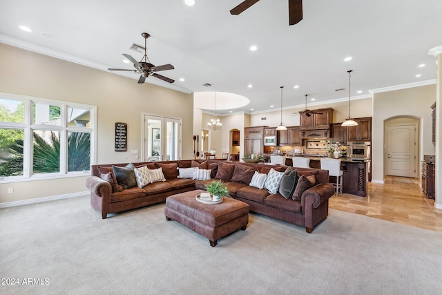 carpeted living room featuring ceiling fan with notable chandelier and ornamental molding