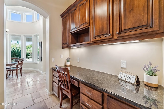 kitchen featuring built in desk and dark stone counters