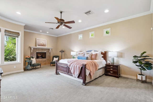 carpeted bedroom with ceiling fan, ornamental molding, and a tiled fireplace