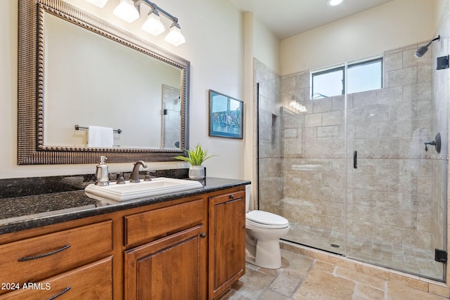 bathroom with a shower with door, vanity, and toilet