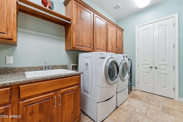 clothes washing area featuring cabinets, washing machine and clothes dryer, and sink