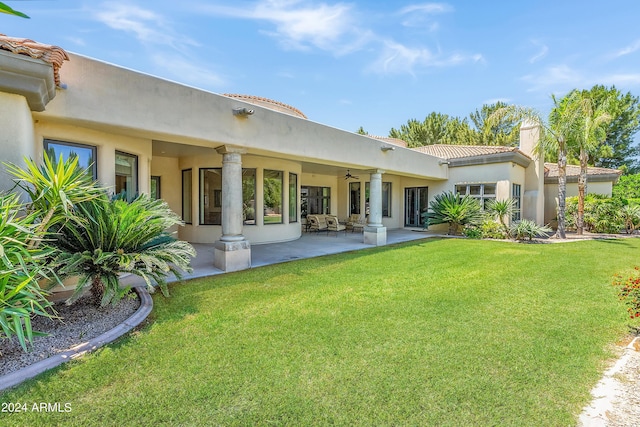 back of property featuring ceiling fan and a yard