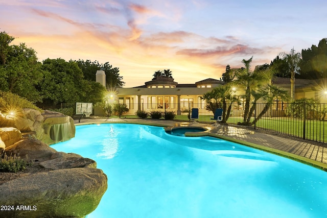 pool at dusk with an in ground hot tub