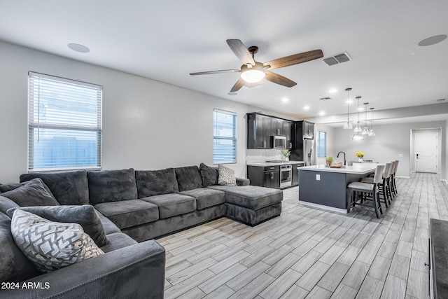 living room featuring ceiling fan, a healthy amount of sunlight, and sink