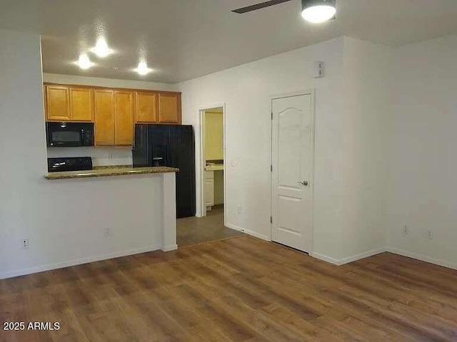 kitchen with kitchen peninsula, ceiling fan, black appliances, and dark hardwood / wood-style flooring