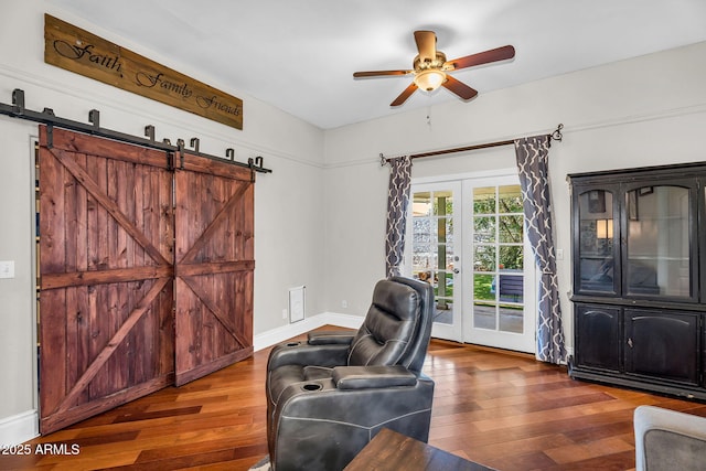 interior space featuring baseboards, ceiling fan, a barn door, and wood finished floors