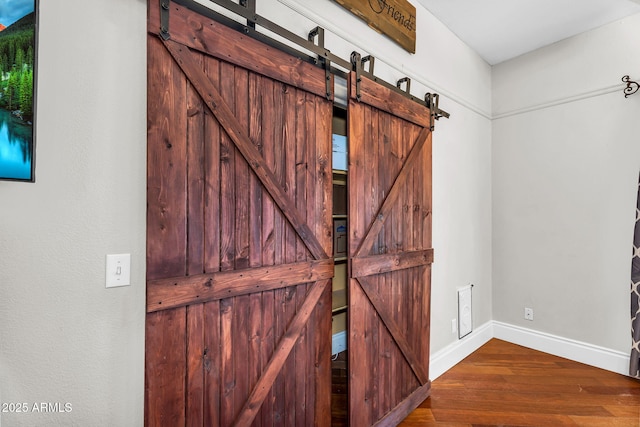 room details with baseboards, a barn door, and wood finished floors